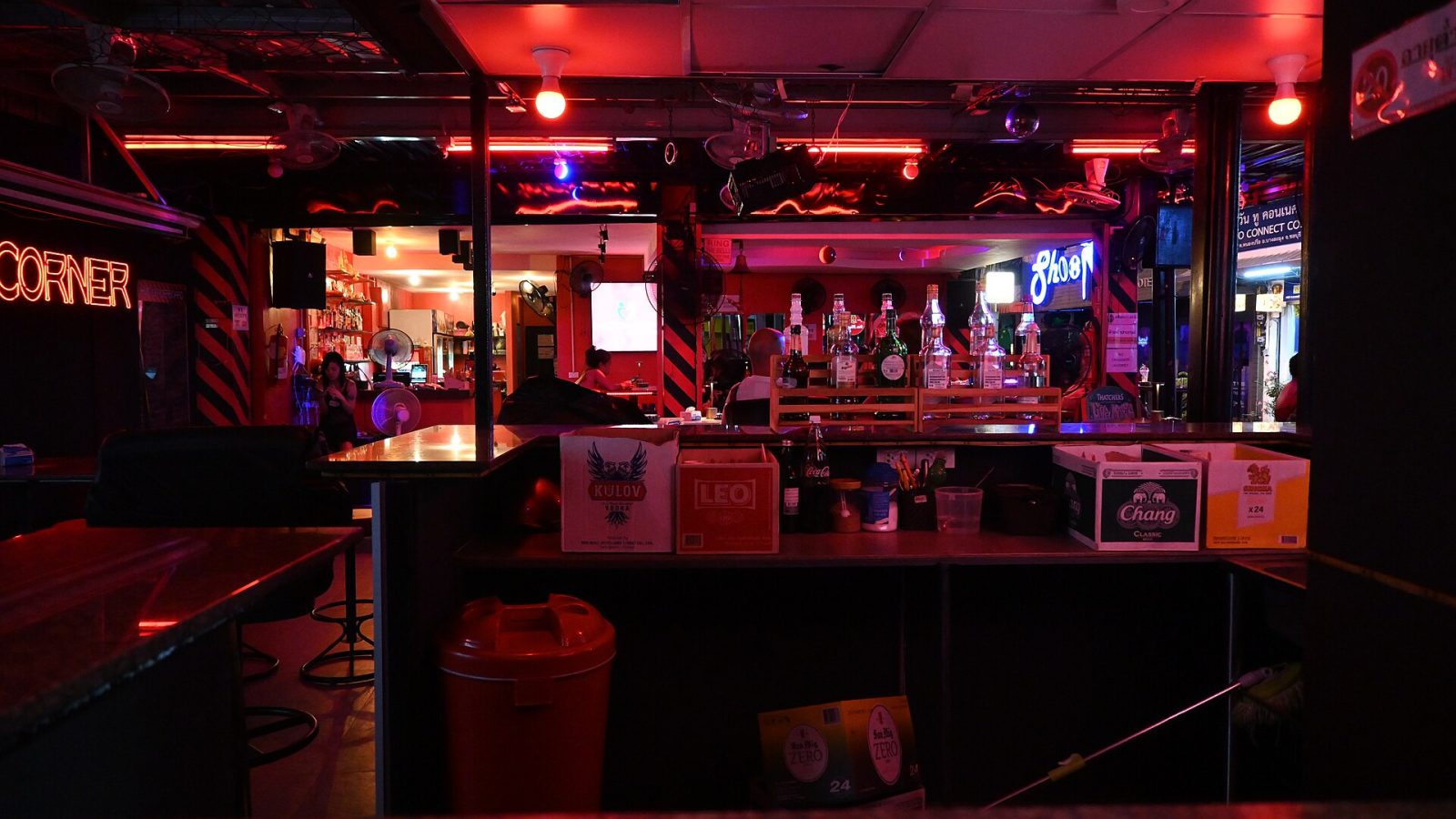 A bar lit with red and purple neon at night